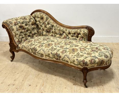 A Victorian carved walnut scroll back chaise longue with button back and scroll end, with brass caps and castors (h. 89cm x l