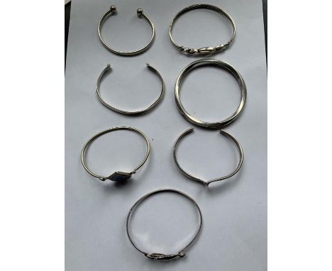 SEVEN MARKED SILVER BANGLES TO INCLUDE A DOLPHIN DESIGN, TEARDROP, SWIRL ETC 
