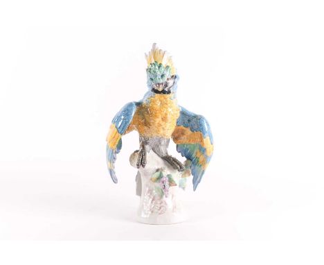 A large Continental ceramic model of a parrot, 20th century, decorated in polychrome enamels and standing on a naturalistic b