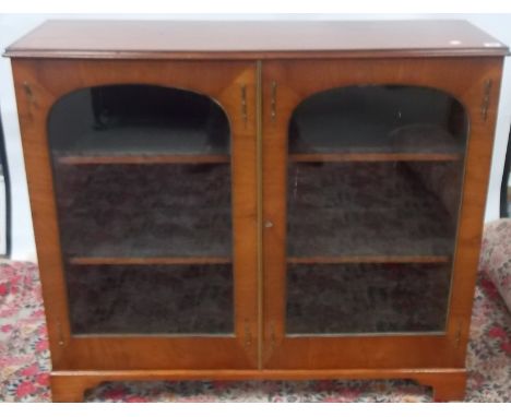 19th Century French walnut veneered low cabinet, the moulded top over a pair of arched glazed doors with brass beading upon b