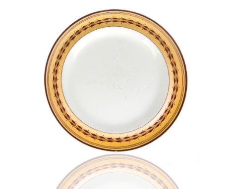 circular with a simplistic beaded rim, the cavetto with a foliate motif against a yellow gold ground in maroon, impressed SPO