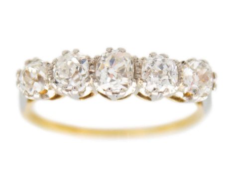 An 18ct and platinum old mine cut diamond set five stone ring. The central diamond of 0.25ct estimated weight, flanked by fou