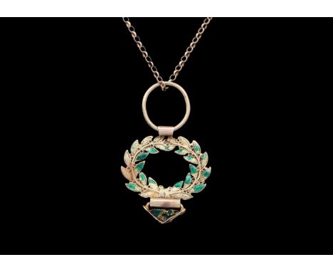 A small 18ct (tested) green enamel applied wreath pendant, on a modern 9ct necklace. Width 22mm, 3.4g; the 9ct chain 2.3g.