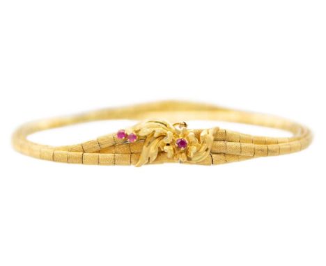 An 18ct ruby set three strand bracelet. The clasp with a flower head button and leaf design, set with three small round cut r