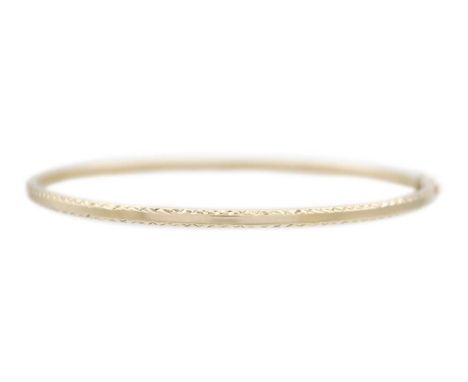 A 9ct white gold bangle. The hollow bangle with diamond cut decoration, width 6cm, 3.51g.