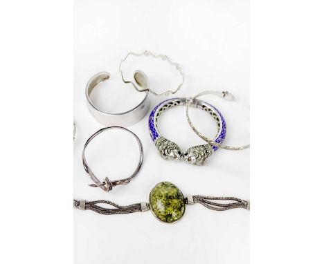 A selection of six silver bangles and an amber set bracelet. To include a 900 silver and blue enamel spring hinged bangle wit