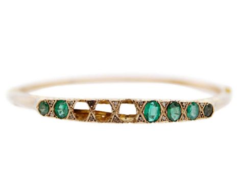 An Edwardian 9ct green paste and diamond point set hinged bangle. Set with six oval cut green paste stones (three deficiant) 