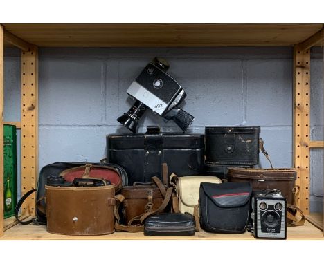 A group of vintage binoculars and a Bolex P4 cine camera.