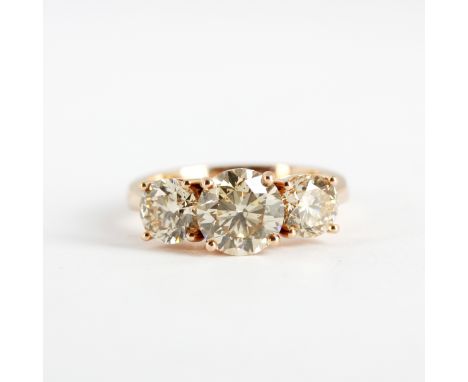 An 18ct rose gold (stamped 750) ring set with three brilliant cut fancy light brown diamonds, centre 2.11ct, sides 1.82ct eac