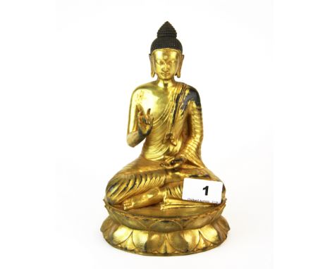 A Tibetan gilt bronze figure of a seated Buddha, H. 21cm.
