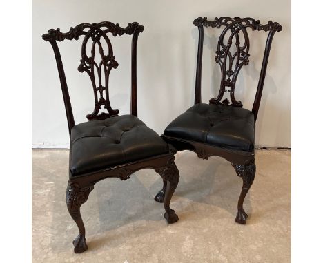 A pair of reproduction carved mahogany hall chairs with dropping button leather seats.