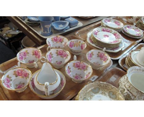 Two trays of teaware items on a white ground with rose and gilt leaf decoration, comprising: teacups and saucers; milk jug; s