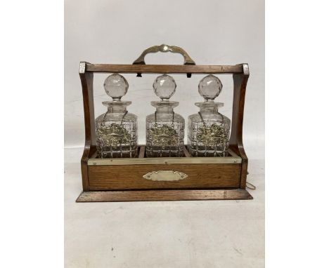 AN GEORGIAN OAK THREE BOTTLE TANTALUS BELIEVED TO BE FROM A STATELY HOME NEAR PENRITH WITH KEY 