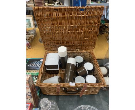 A WICKER PICNIC HAMPER WITH 'PATIOWARE' FLASKS, STORAGE BOXES, PLATES AND CUPS FROM TIMOTHY WHITES 