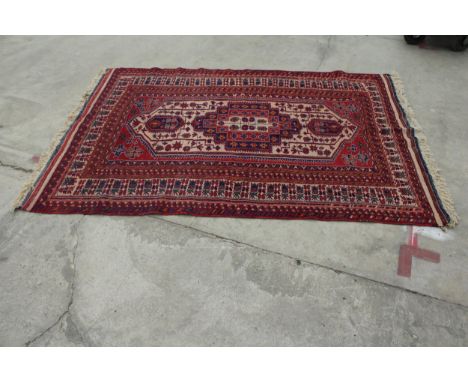 A VINTAGE RED PATTERNED FRINGED RUG 