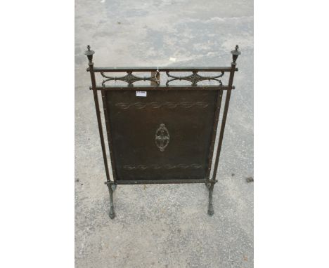A BRASS ARTS AND CRAFTS FIRESCREEN WITH EMBOSSED DECORATION, FINIALS AND CLAW FEET 