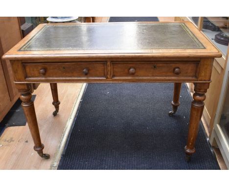 An early 20th century light oak olive green tooled leather topped office desk with four turned baluster legs, with brass cast