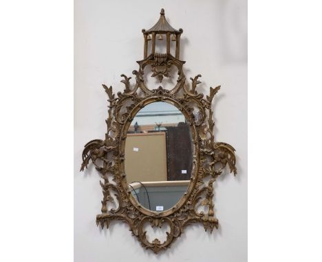 An 18th Century style gilt mirror, wooden in construction, with Eastern style building, of bolsa wood bells and heavy foliage