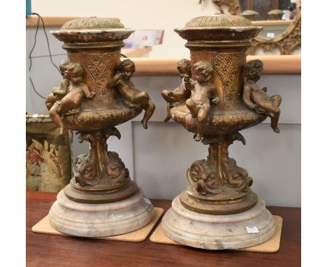 A pair of 19th Century candle holders which have been converted into lamp bases, on marble stands with dolphin and putti deta