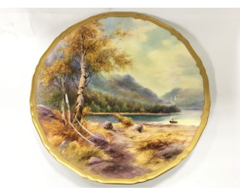 A Royal Worcester plate with gilt rim depicting a lake by H Davis