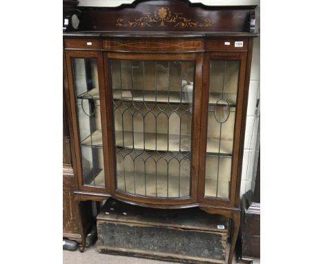 An Edwardian inlaid Mahogany display cabinet the raised back with folate scrolls above a bow fronted lead light glazed door o