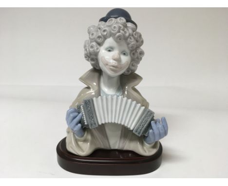 A Lladro figure of a clown playing an instrument on a wooden base 