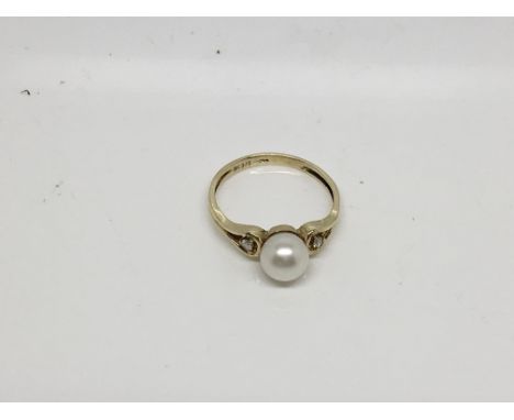 A yellow gold culture pearl flanked by diamond either side. Size N.