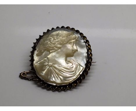 A mother of pearl broach depicting a classical maiden 