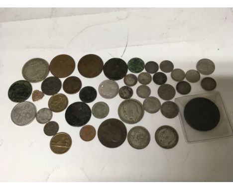 A large silver coin along with a collection of various other coins. 