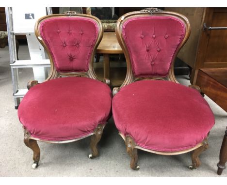 A pair of Victorian nursing chairs with red button back upholstery.