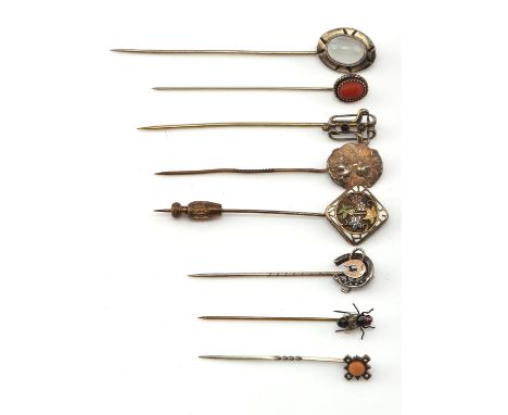 Eight stick pins mainly set in silver, including a silver and oval cabochon moonstone stick, a silver repoussé cameo and base