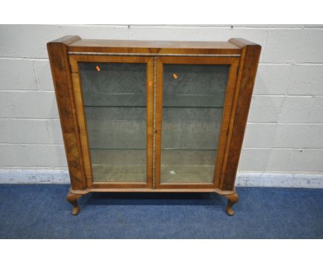 AN ART DECO WALNUT DISPLAY CABINET, the double glazed doors with geometric etched glass, enclosing two glass shelves, on cabr