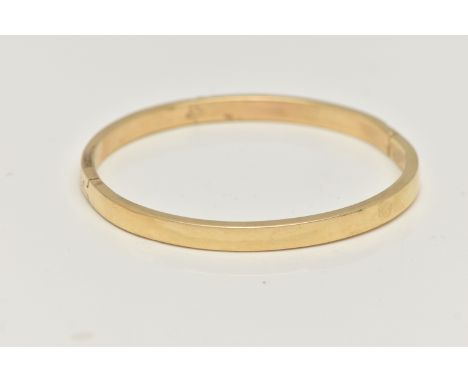 A YELLOW METAL HINGED BANGLE, a hollow bangle fitted with an integrated push pin clasp, approximate width 5mm, stamped 585, a