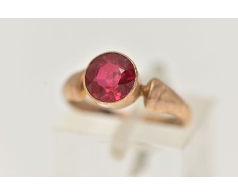 A YELLOW METAL RED PASTE RING, circular cut red paste, milgrain collet setting, to a polished band, stamped 9ct, ring size J,