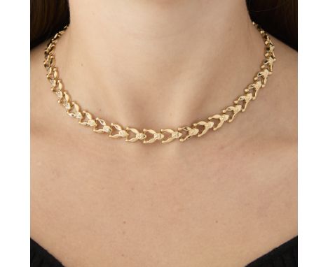 14k yellow gold fancy link necklace. Comprised of chevron links with circular and triangular accent details. With a box clasp