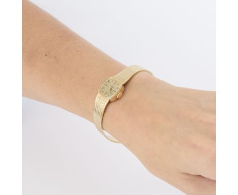 14k yellow gold ladies Omega wristwatch. With oblong rectangular gold tone dial on a finely articulated, integrated 14k yello