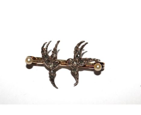 A bar brooch with two diamond set swallows together with a costume brooch in the form of an enamelled flask 