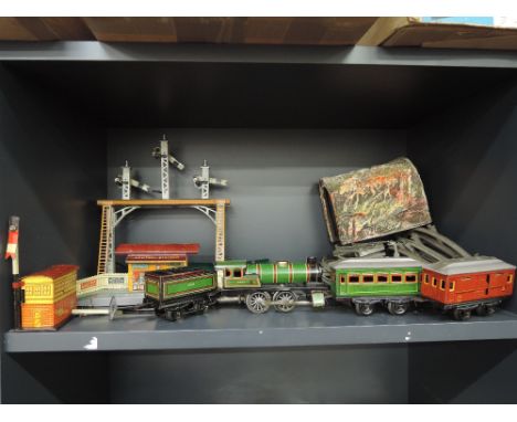 A shelf of JDN Distler and similar tin plate 0 gauge including 0-4-0 loco and tender, two carriages, station, signals etc and