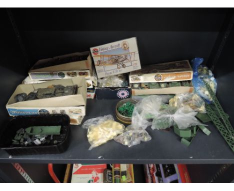 A shelf of plastic military kits and figures including Airfix and a small selection of miniature diecast military tanks