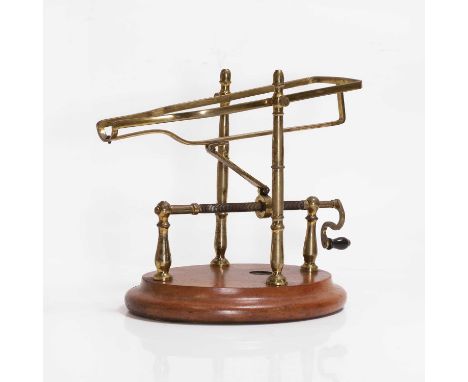 A wine cradle, the brass turned frame with a winding mechanism, on an oval wooden stand,21cm wide24cm highCondition Reportlab