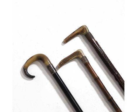 Three walking sticks, comprising:an example with an antler handle, a cast white metal collar and a bamboo shaft,another with 