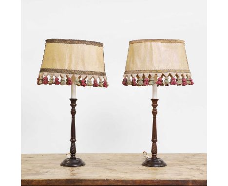 A pair of mahogany candlestick table lamps, 20th century, each with a turned and fluted stem on a turned base, with an oval t