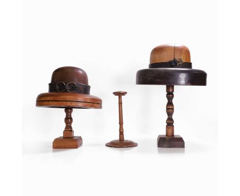 Two milliner's treen hat formers, 19th century, each on a stand and with a leather buckled band,28 and 30cm high, anda wig st