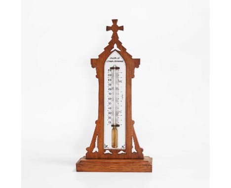 A Victorian Gothic oak-framed thermometer, c.1870, by Salom &amp; Co., London and Edinburgh, with a glass register, on a plin