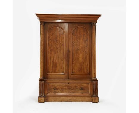 A Victorian mahogany wardrobe, the moulded cornice over two arched panelled doors between turned columns, enclosing hanging s