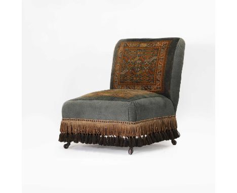 A Victorian low chair, c.1890, with carpet upholstery and a bullion tassel fringe, on turned ebonised legs and castors,63cm w