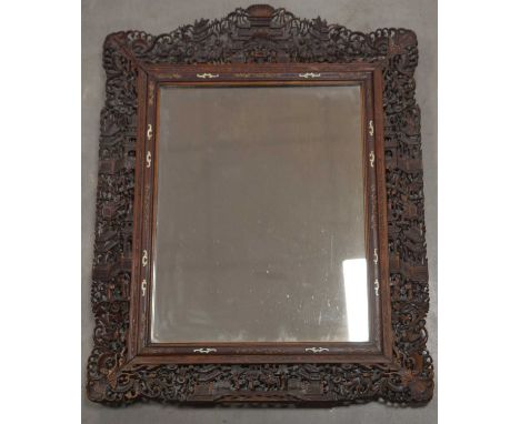 A late 19th-Early 20th century ornately carved Chinese mirror, the crest, sides and apron with carved fretwork scenes of figu