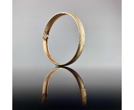 A 9ct gold bangle with textured front, weight 7g.From the Estate of Julia & Sven Berlin