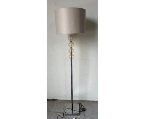A chrome floor lamp with amber orb detail 