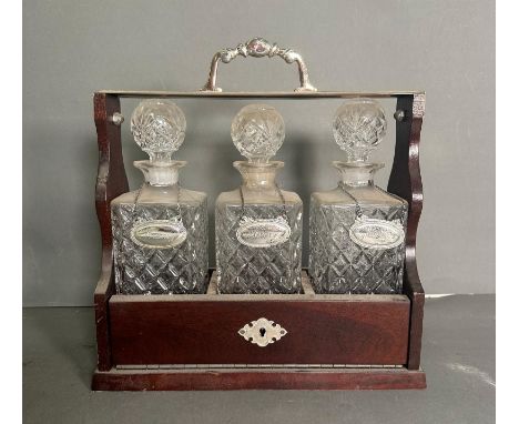 A mahogany tantalus with three cut glass decanters 